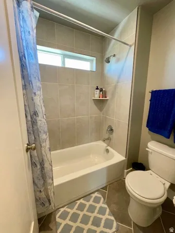 Upstairs full bath; Bathtub and shower combination with a single-handle faucet, integrated shelving, and a horizontal window