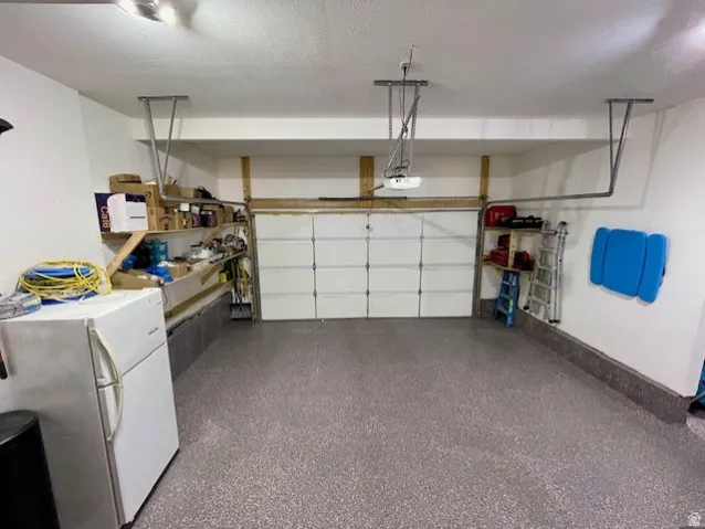 Large Garage with a sectional overhead door, built-in shelving, and a speckled epoxy floor