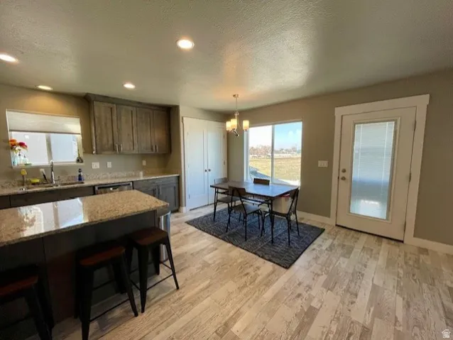 Kitchen with granite countertops, wood-finish flooring, recessed lighting, and a built-in dishwasher with a large pantry and dining area.