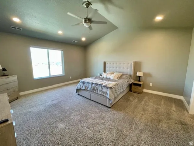 Primary bedroom! Recessed lighting, ceiling fan, vaulted ceiling, large window with views, and wall-to-wall carpeting