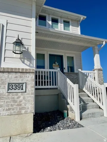 Exterior featuring horizontal siding, brick veneer accents, a covered entry, an outdoor wall lantern, and concrete steps with white railings