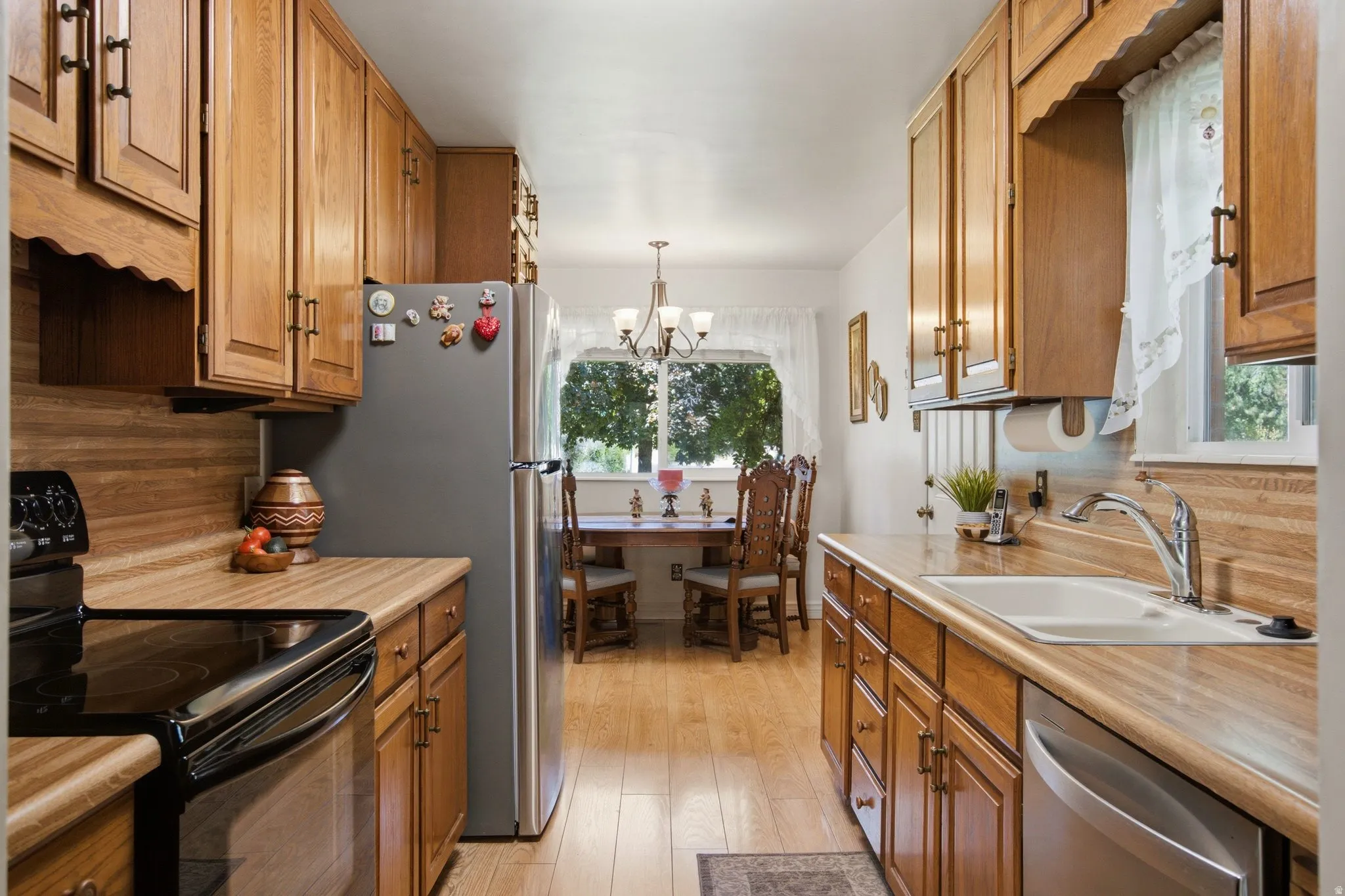 Galley kitchen with wood-finish cabinetry, stainless steel appliances, and a built-in dishwasher