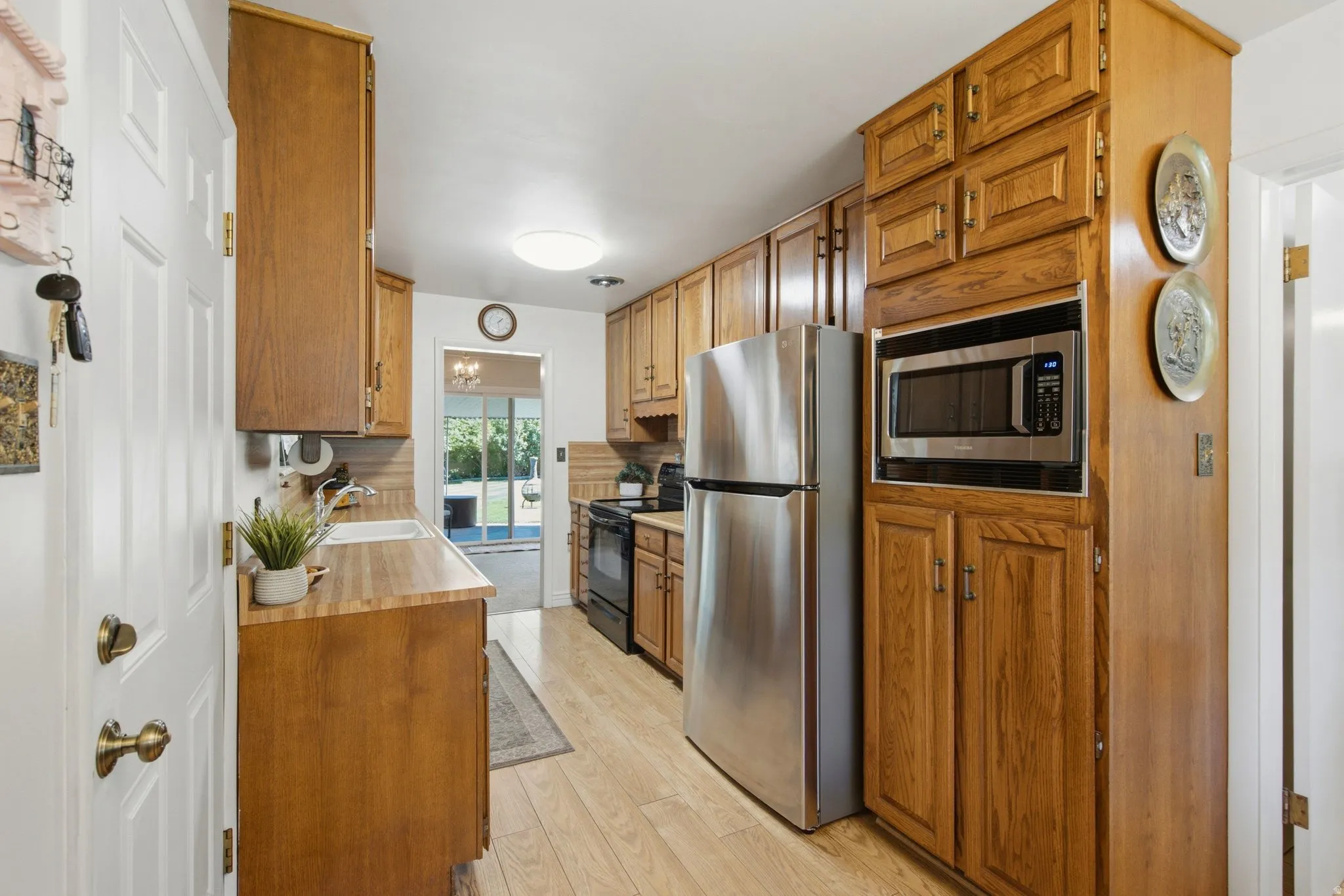 Kitchen featuring wood-finish flooring, ample wood cabinetry, stainless steel refrigerator, built-in microwave, and wood-finish countertops