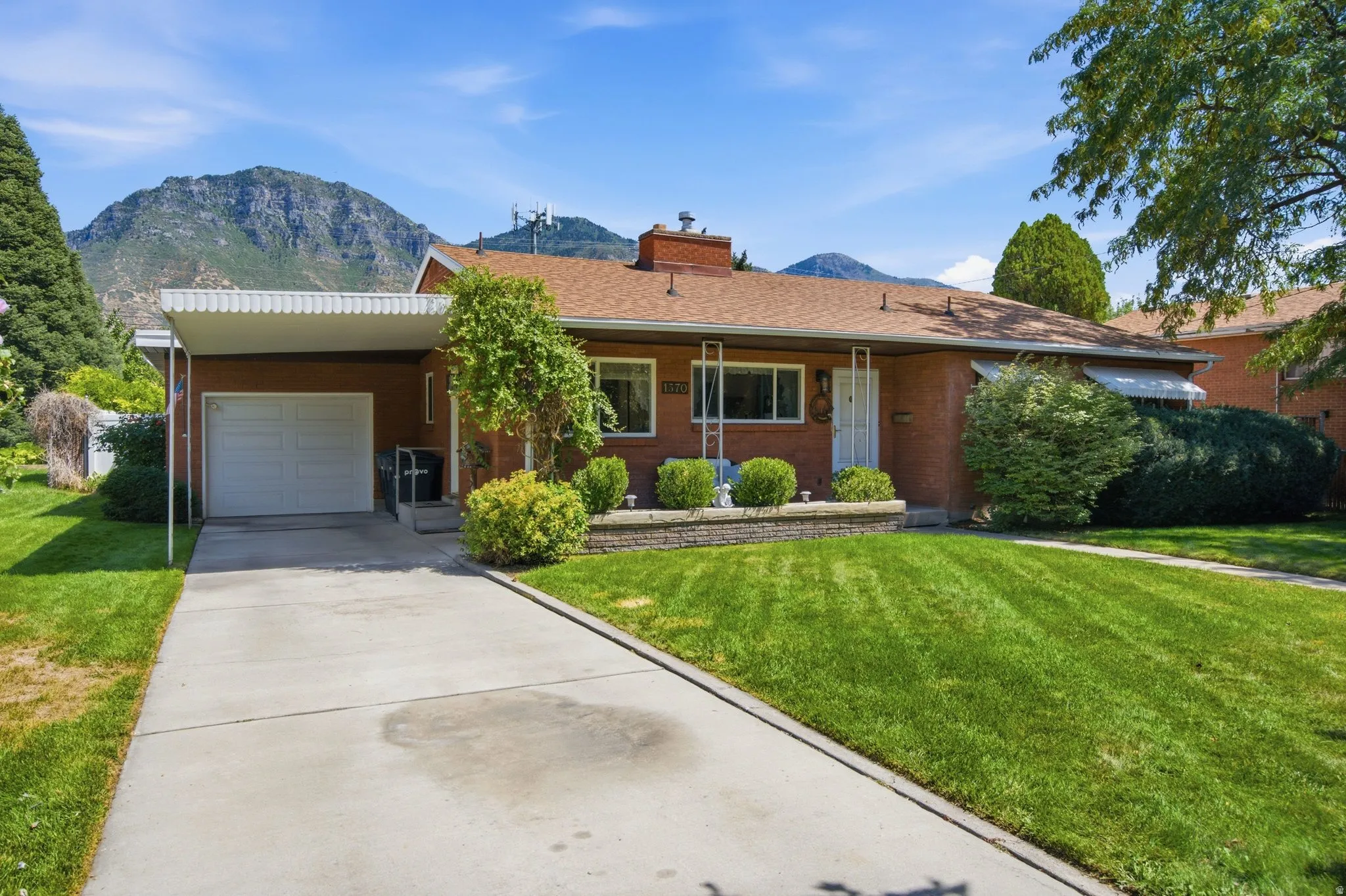 Brick exterior with a covered carport, attached garage, and a concrete driveway