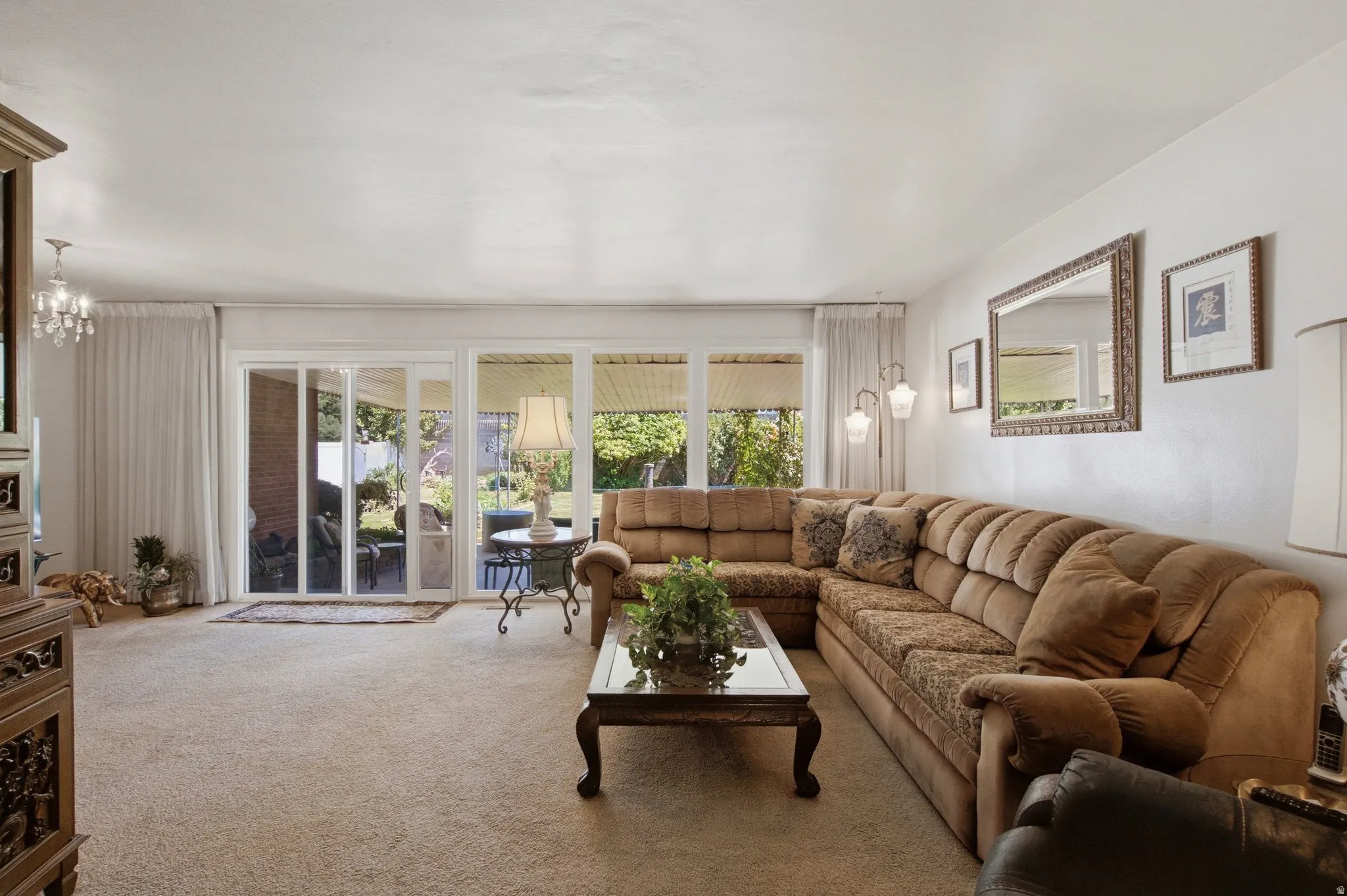 Sliding glass doors opening to the exterior, expansive wall-to-wall carpeting, and a chandelier fixture