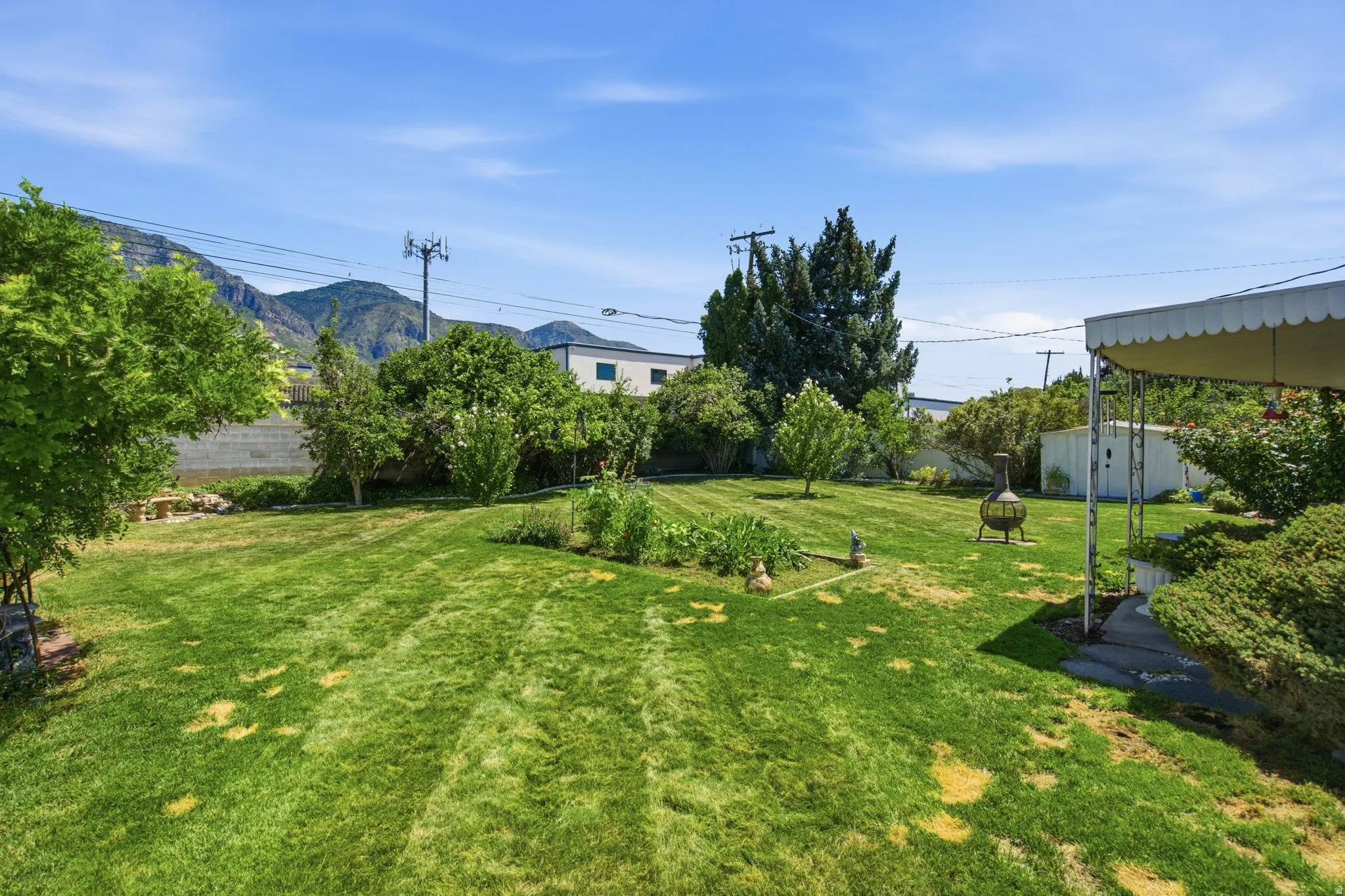 Expansive green lawn with mature trees and a shaded patio area