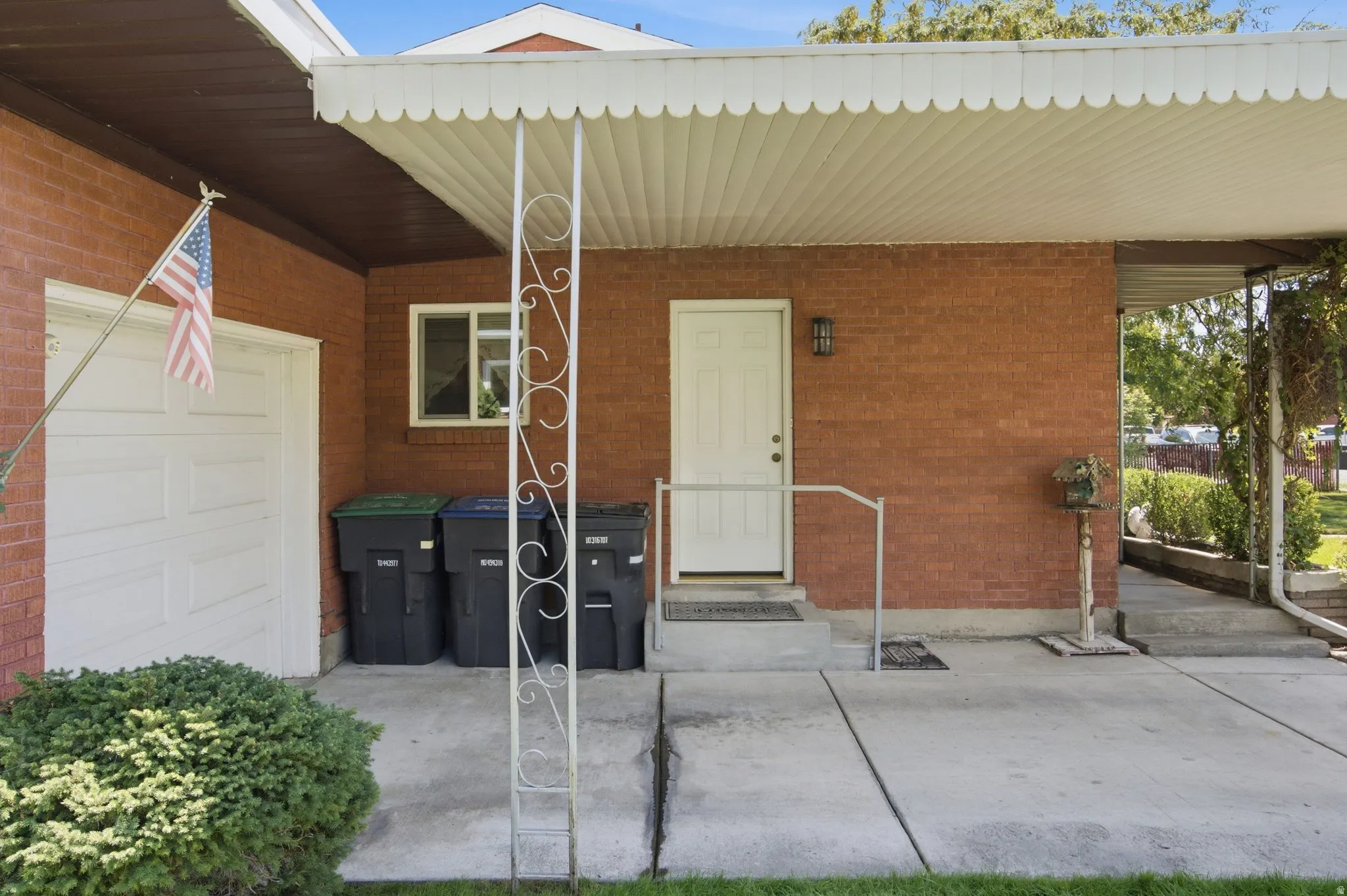 Brick exterior with an attached garage, covered entryway, and mature landscaping