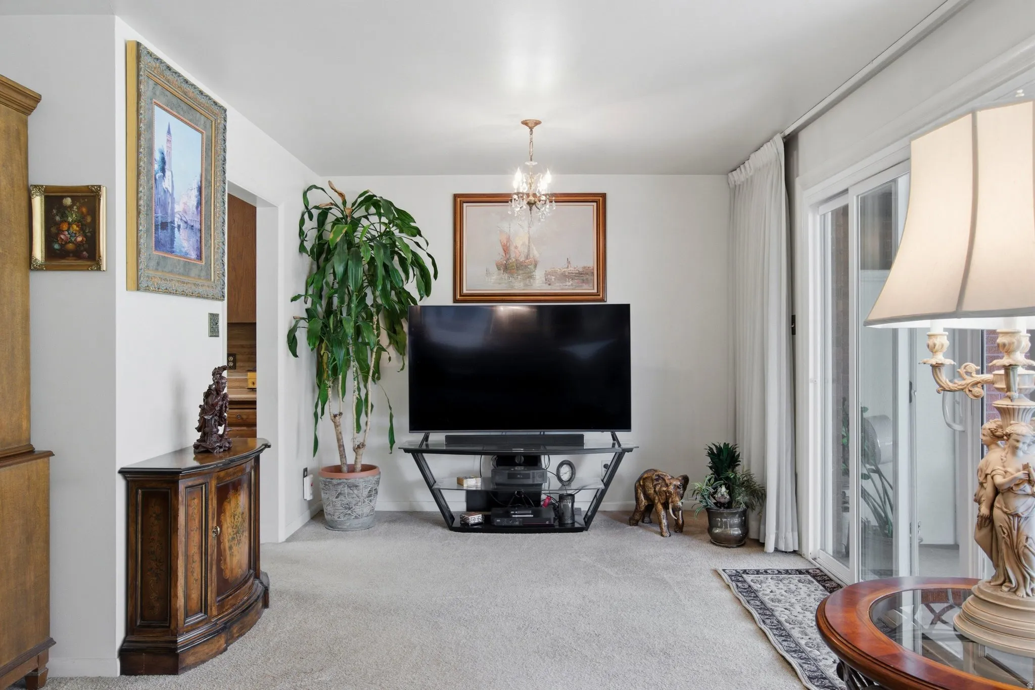 Plush carpet flooring, chandelier lighting, and a sliding glass door