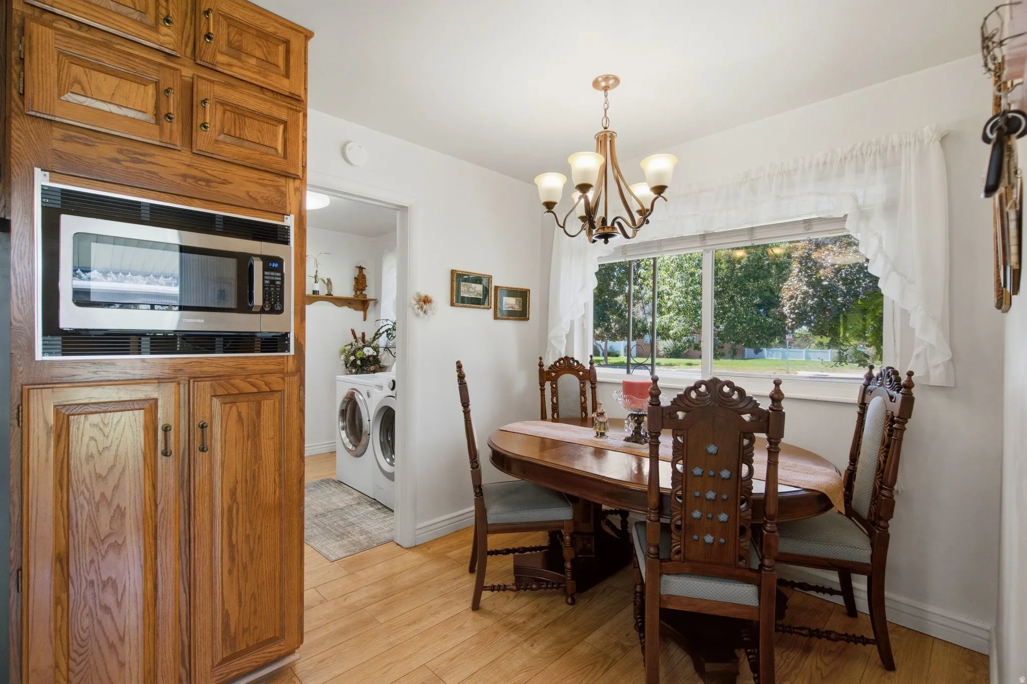 Hardwood-finish flooring, built-in microwave, integrated laundry appliances, and an ornamental chandelier