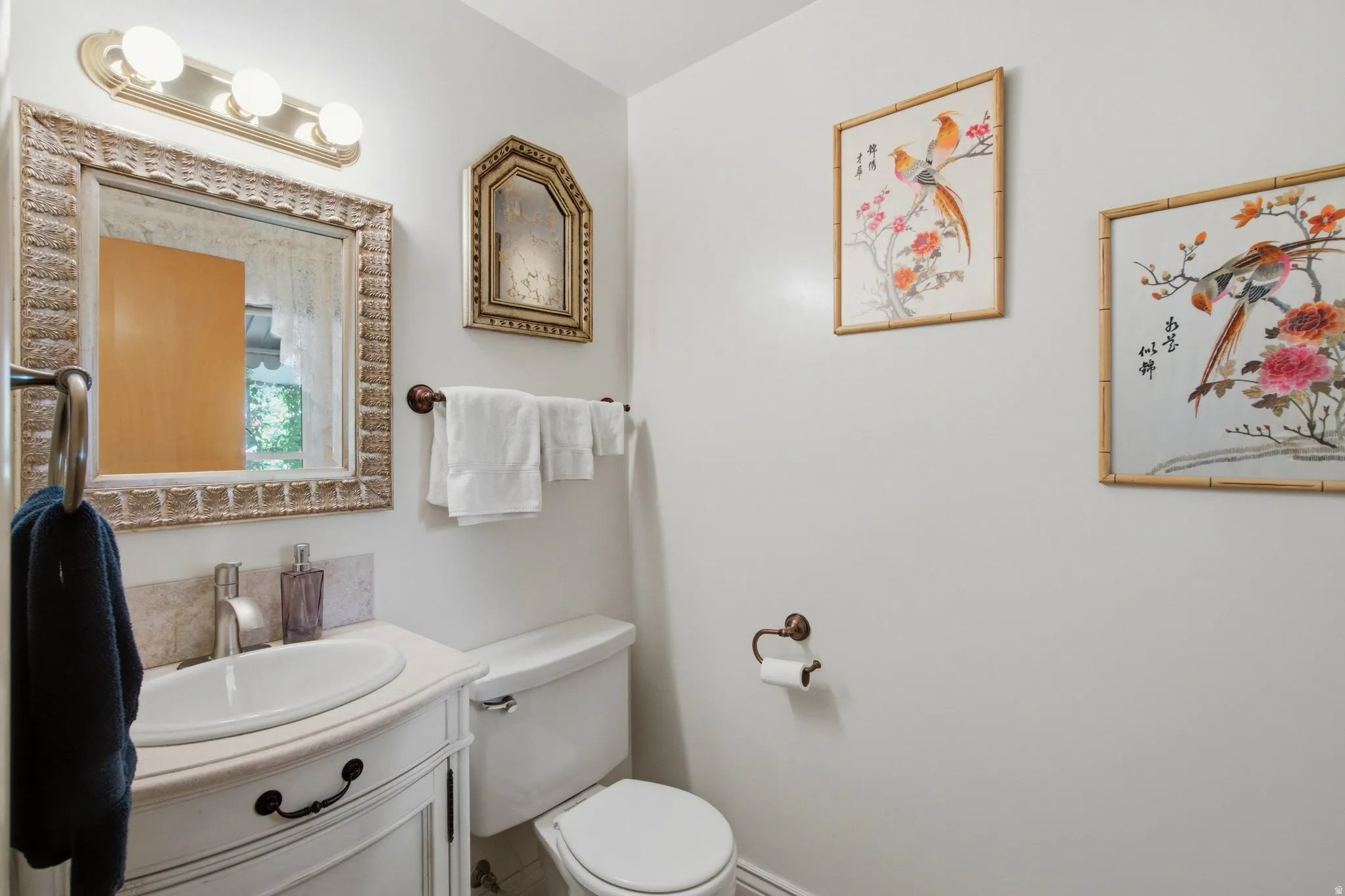 White vanity with a single basin sink, brushed nickel faucet, and a decorative framed mirror