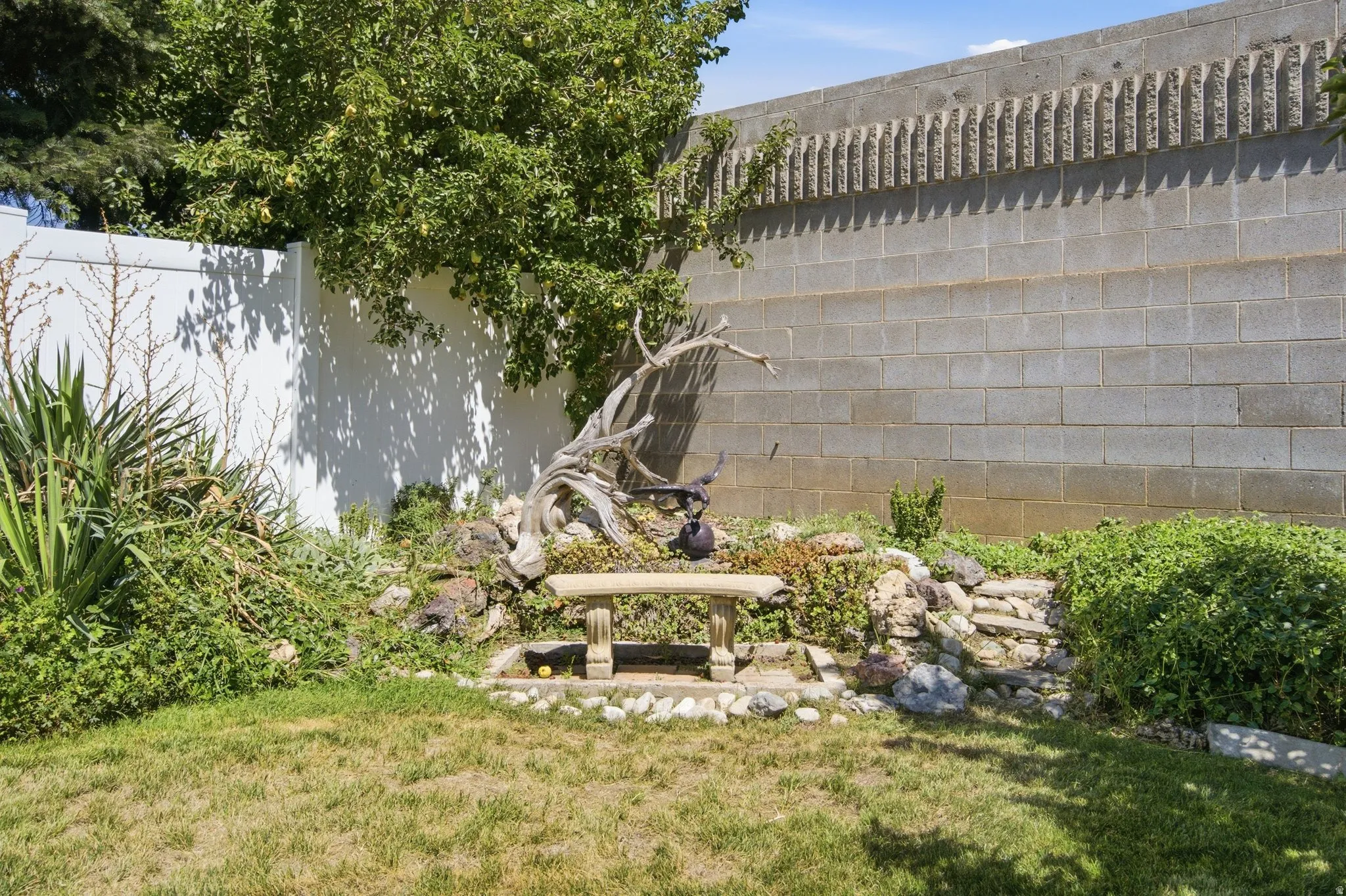 Landscaped area featuring a stone bench, decorative rock formations, and mature trees