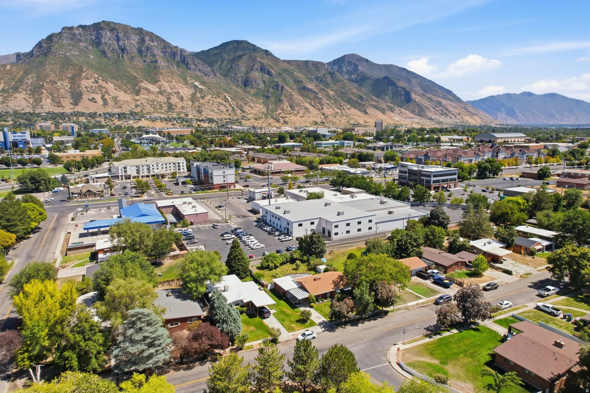 Community landscape featuring mountainous terrain, diverse architectural styles, mature trees, and paved roadways