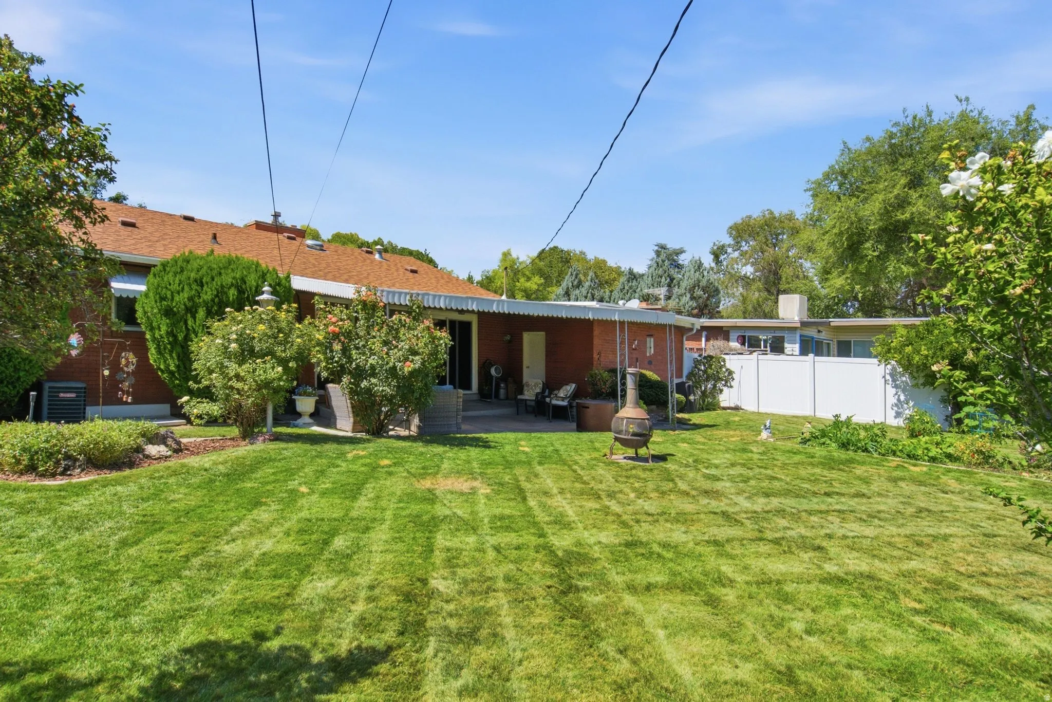 Expansive green lawn with mature landscaping, covered patio, and brick exterior