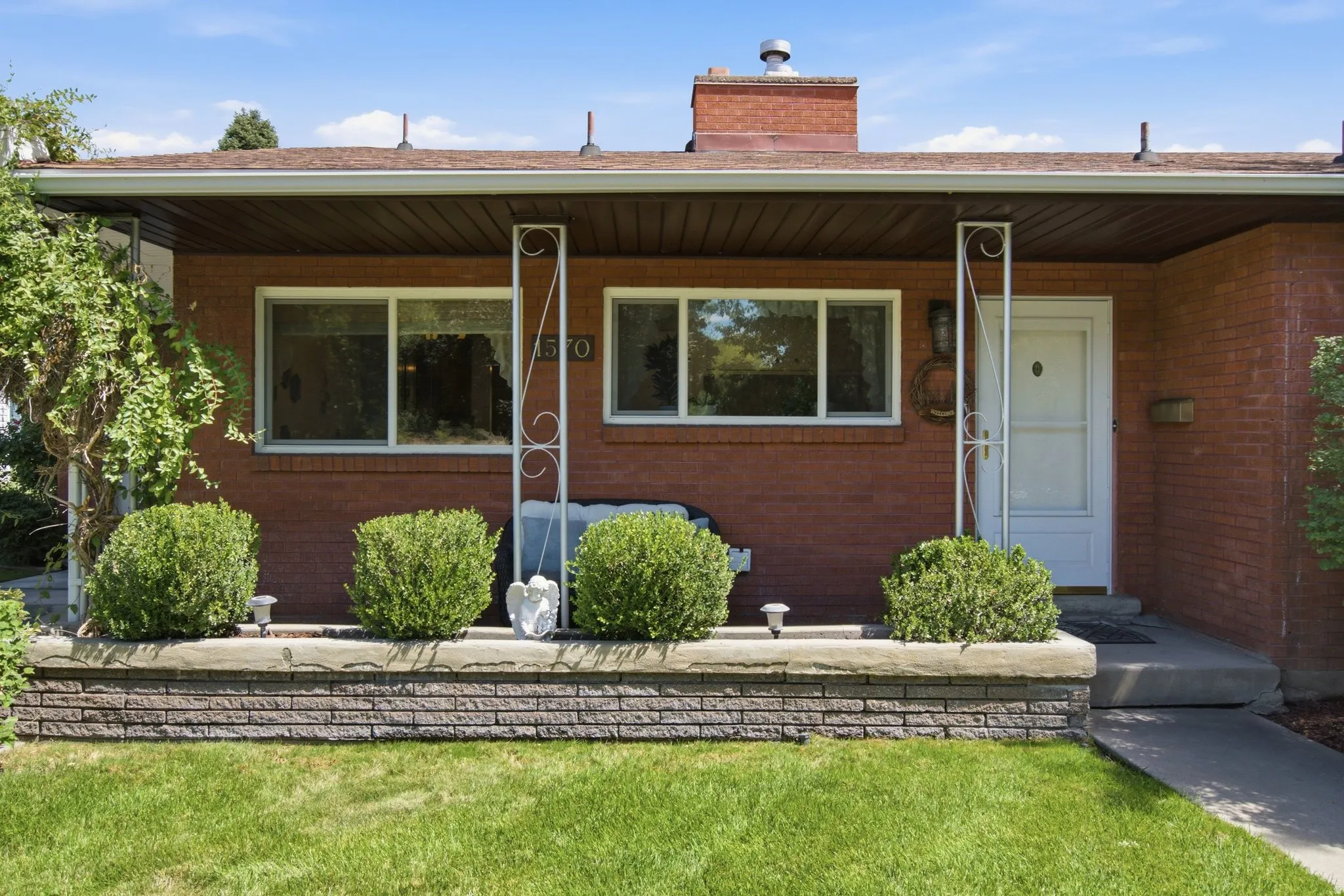 Brick exterior with a white entry door, covered front porch, and decorative metal columns