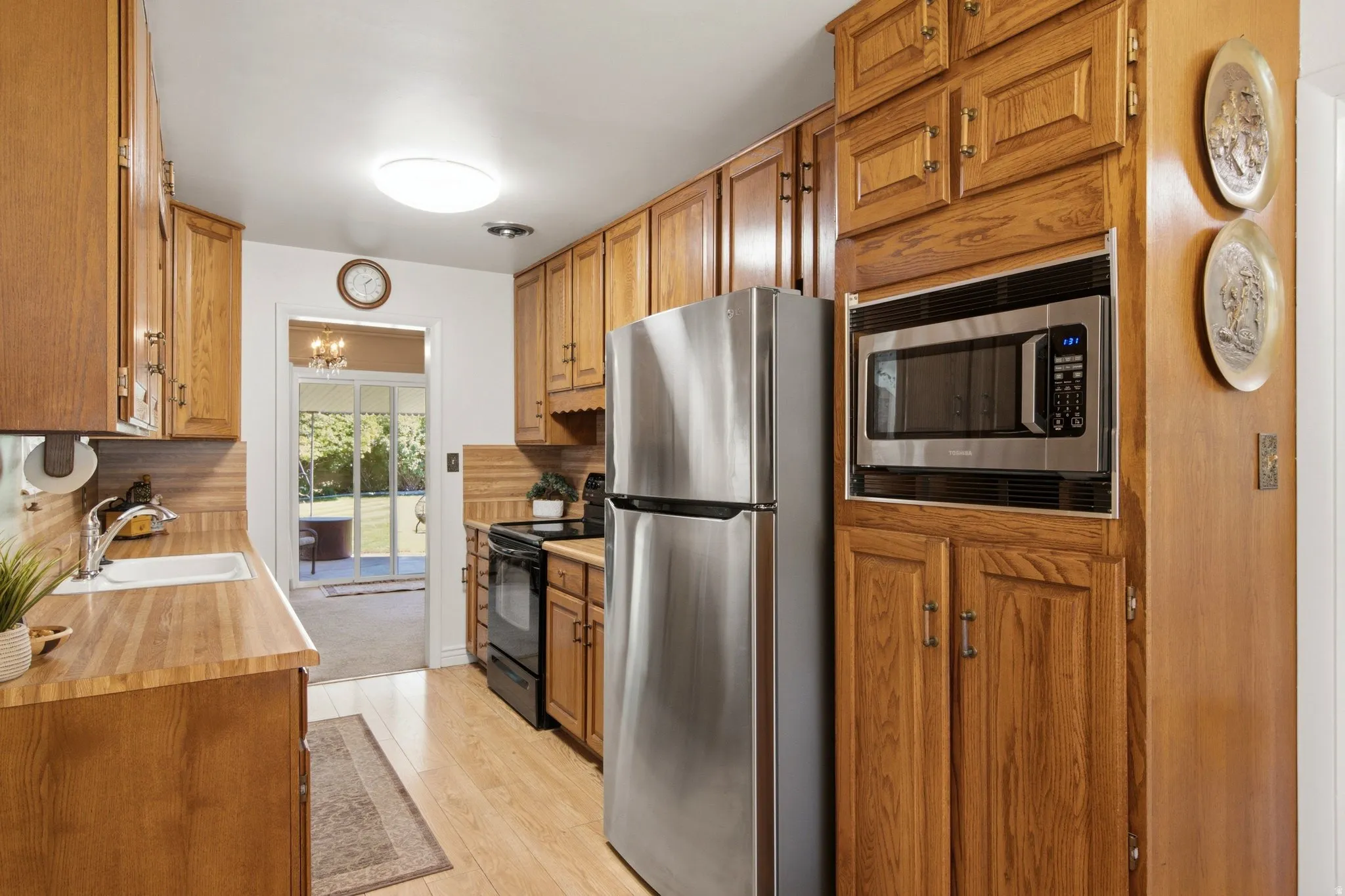 Galley kitchen featuring wood cabinetry, stainless steel appliances, wood-finish countertops, and wood-finish flooring