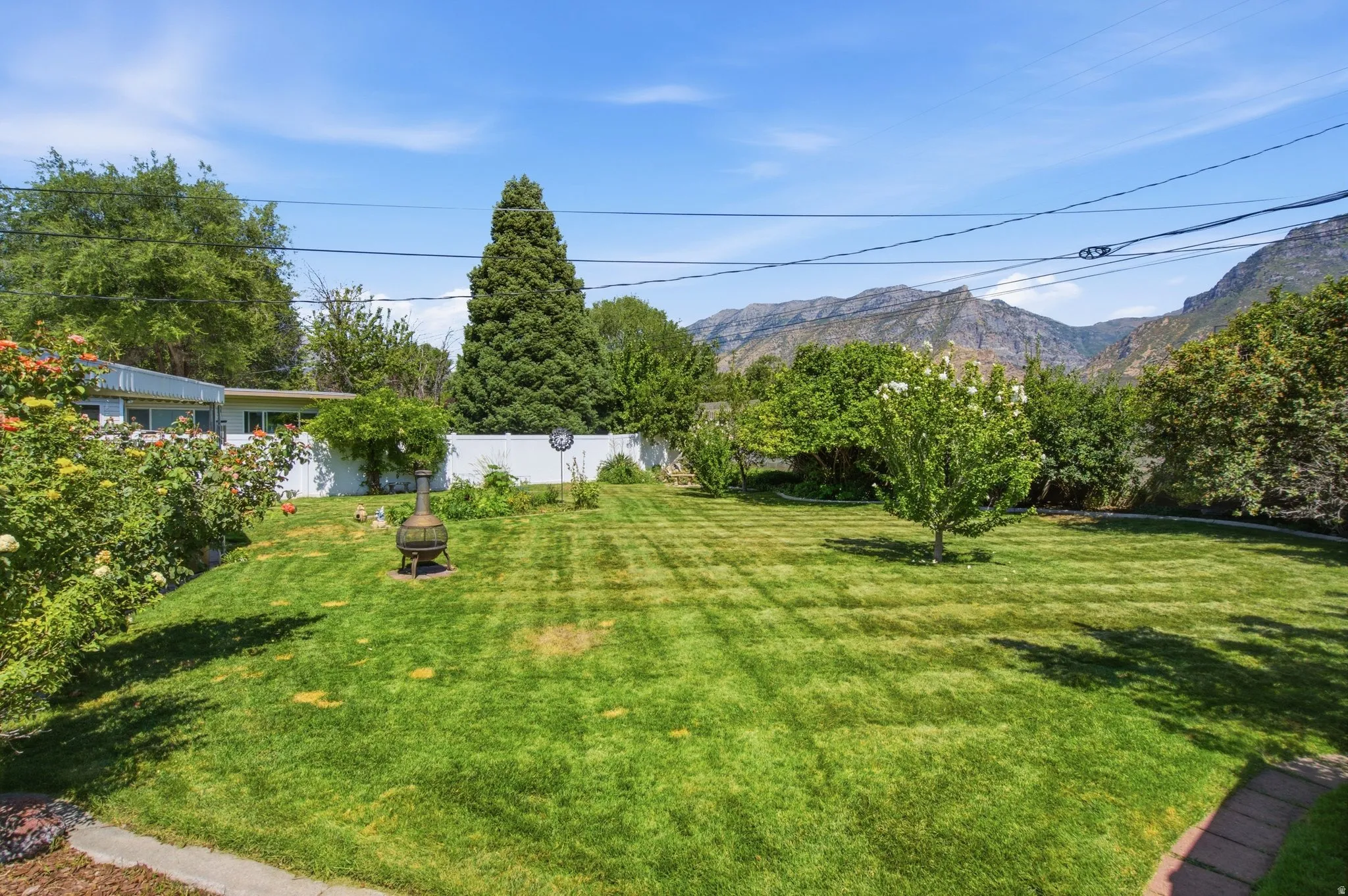 Spacious backyard with manicured lawn, established shrubs, and mature trees