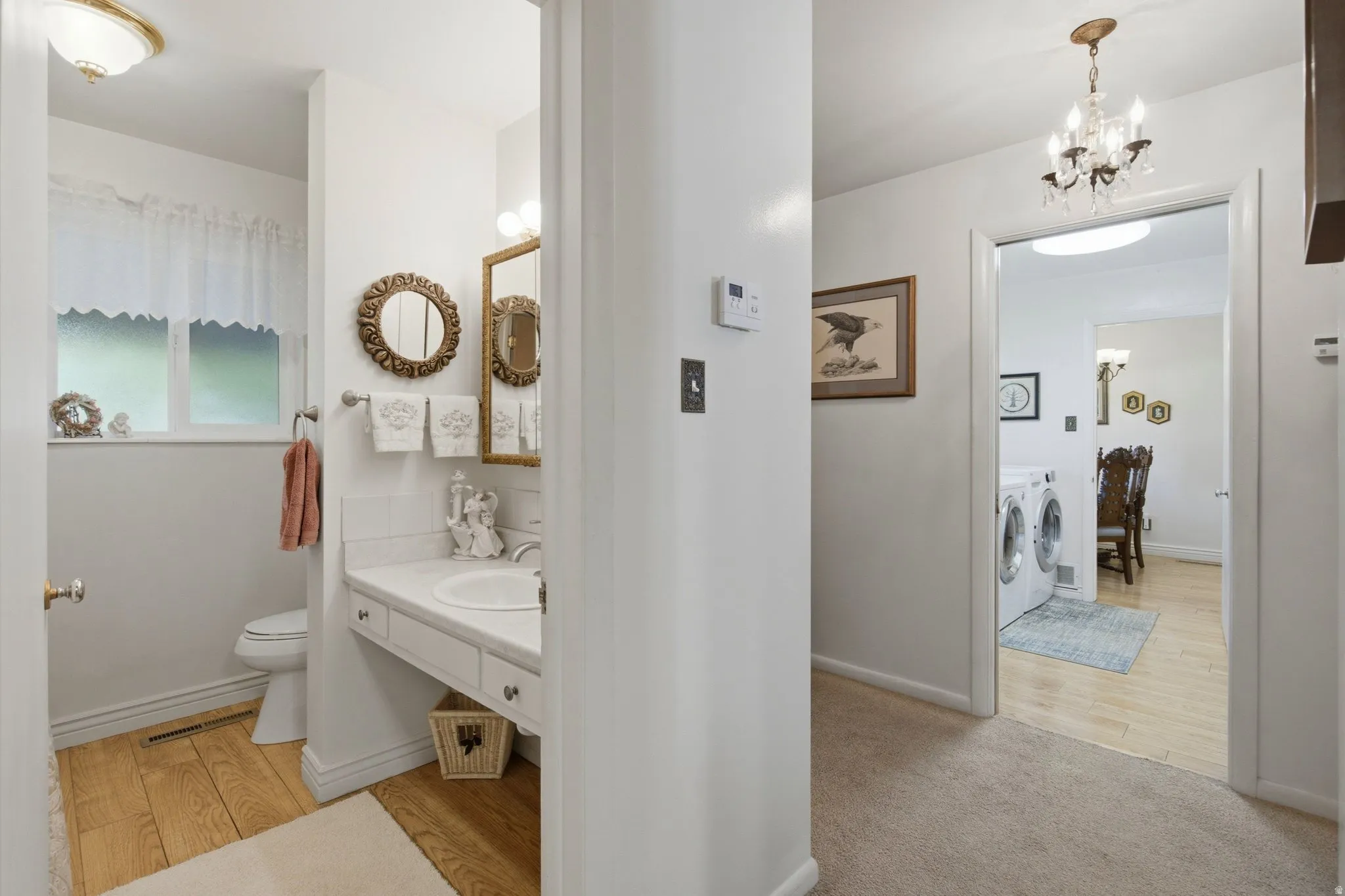 Vanity with white countertop and integrated sink, recessed lighting, wood-finish flooring, and a chandelier fixture