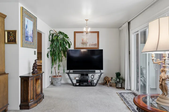 Plush carpet flooring, chandelier lighting, and a sliding glass door