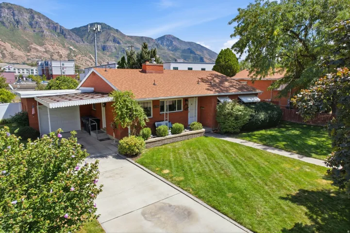 Brick exterior residence with a covered carport, concrete driveway, and front lawn