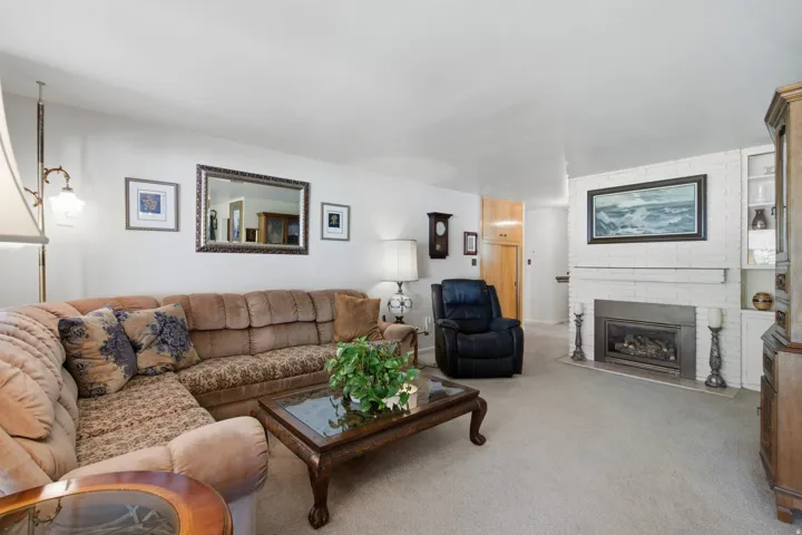 White brick fireplace with a mantle, built-in shelving, and a gas insert