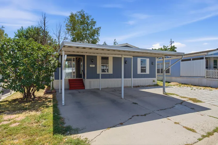 Exterior featuring blue siding, white trim, and a covered carport