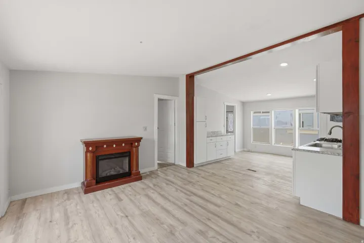 Wood-finish flooring, recessed lighting, white cabinetry, granite countertops, and a built-in fireplace