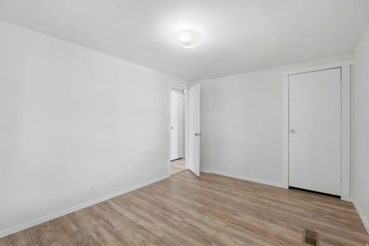 Wood-finish flooring, white walls, white doors, and a ceiling-mounted light fixture