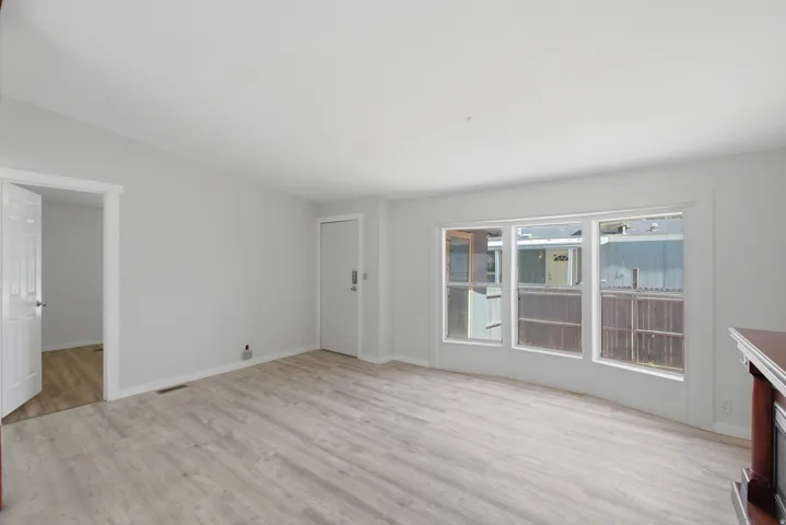 Light-toned wood-finish flooring, white trim, and a white interior door