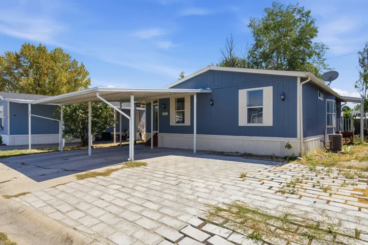 Exterior featuring a carport, blue siding, white trim, and a paved driveway