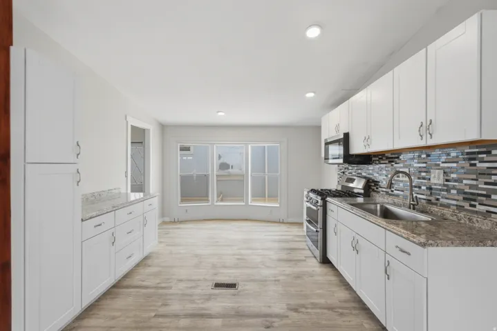 Kitchen featuring white cabinetry, stone-finish countertops, stainless steel appliances, and wood-finish flooring