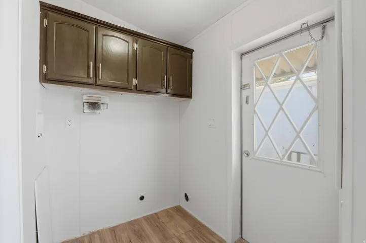 Wood-finish flooring, overhead cabinetry, and white paneled walls