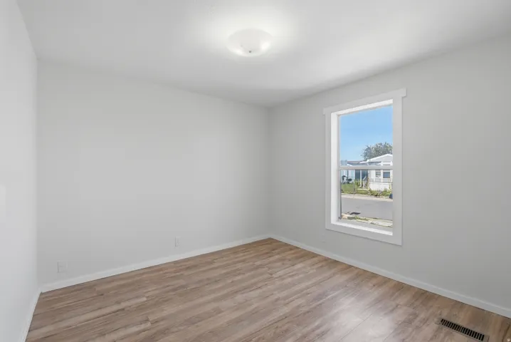 Wood-finish flooring, white walls, single window with white trim, and a ceiling-mounted light fixture