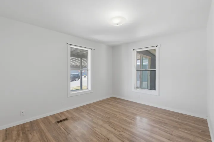 Wood-finish flooring, white walls, and two windows