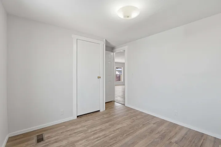 Wood-finish flooring, white trim, and a semi-flush mount ceiling fixture