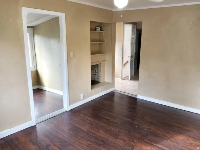 Wood-finish flooring throughout, built-in shelving, fireplace feature, and ceiling-mounted light fixture