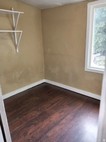 Wood-finish flooring, white trim, built-in shelving, and a white-framed window