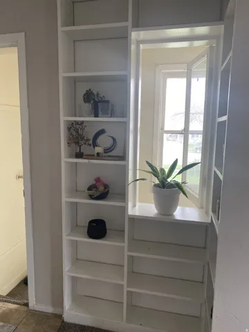 Built-in shelving unit with multiple display shelves, integrated window, and painted finish