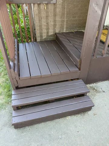 Entry porch featuring wood decking and steps, with a block wall facade