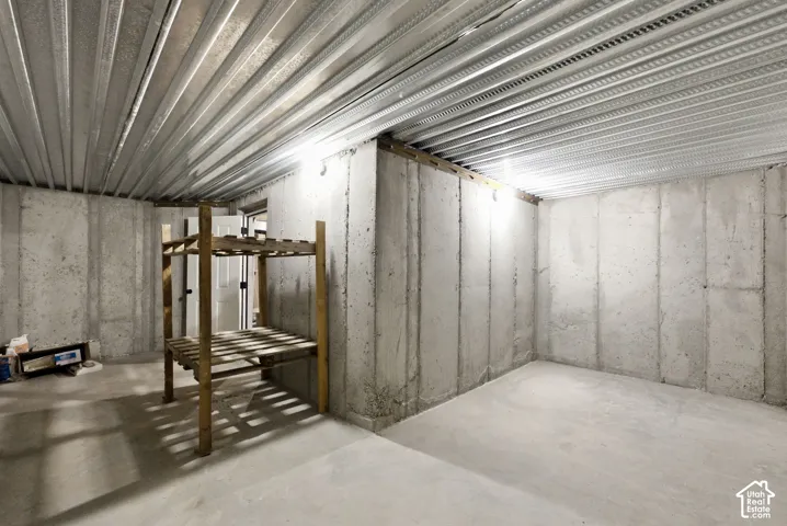 Unfinished basement with concrete walls, concrete flooring, and metal ceiling joists