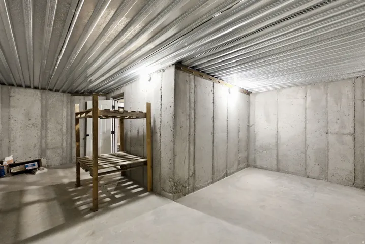 Unfinished basement with concrete walls, concrete flooring, and metal ceiling joists
