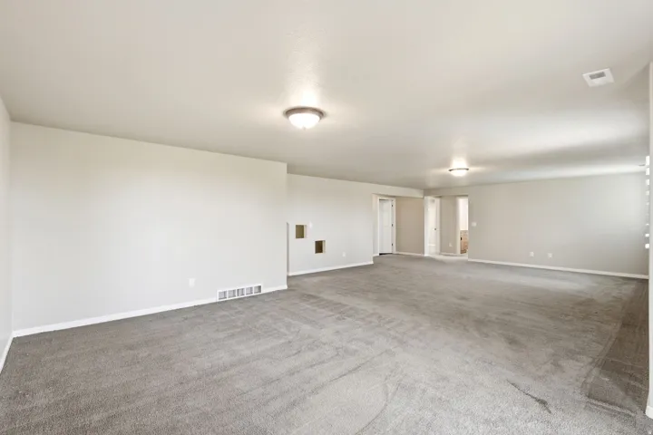 Spacious room with light gray carpeting, neutral wall color, and recessed ceiling lighting