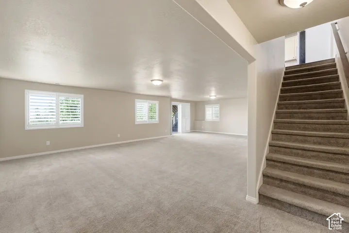 Spacious room with plush carpeting, recessed lighting, white window shutters, and direct access to an exterior area