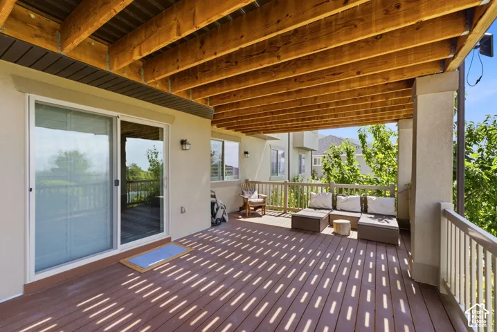 Covered outdoor deck with exposed wood beam ceiling, composite decking, and sliding glass door access