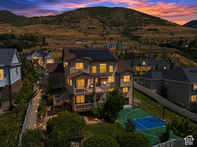 Two-story property with multiple balconies, a dedicated sports court, and an expansive mountain backdrop