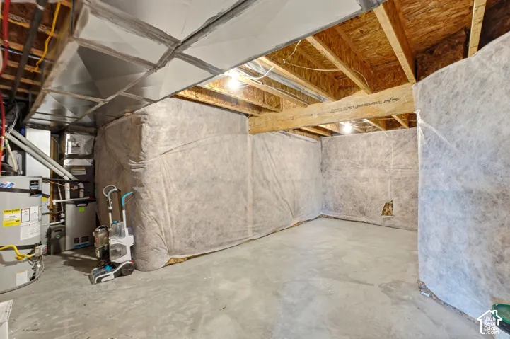 Unfinished utility space featuring exposed wooden floor joists, concrete flooring, insulated foundation walls, and metal HVAC ductwork
