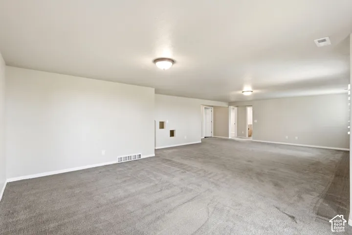 Spacious room with light gray carpeting, neutral wall color, and recessed ceiling lighting