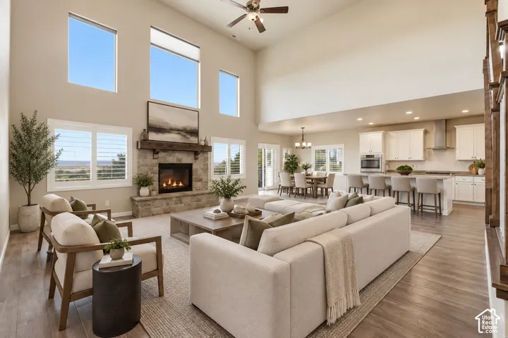 Virtually Staged: Open-concept great room with soaring ceilings, a stone fireplace, and wood-finish flooring