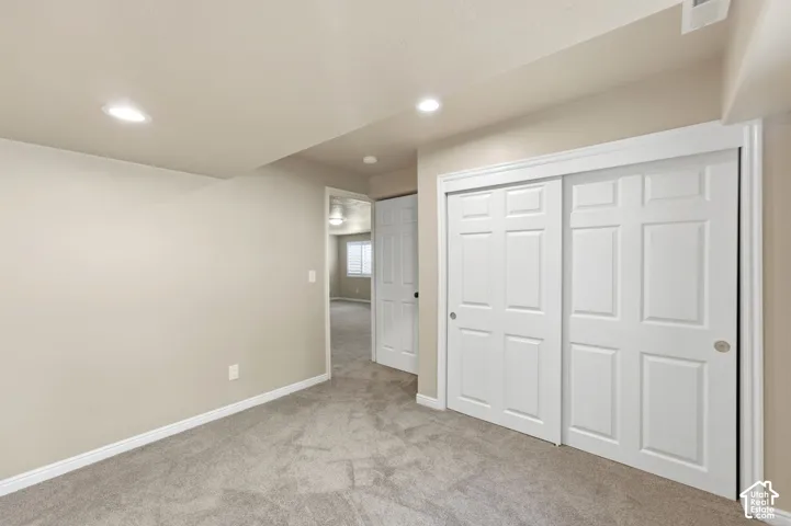 Recessed lighting, light-toned walls, and grey carpeting