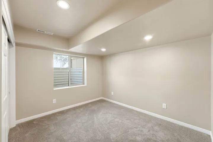 Recessed lighting, wall-to-wall carpeting, and a window with a window well