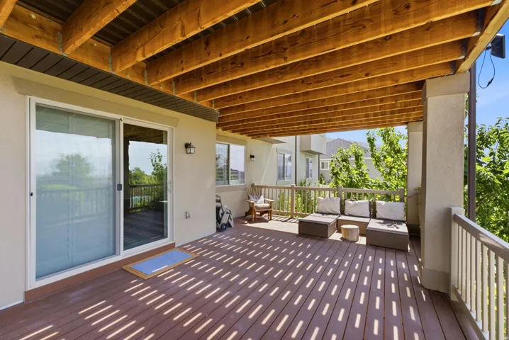 Covered outdoor deck with exposed wood beam ceiling, composite decking, and sliding glass door access